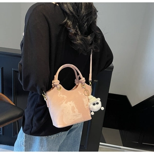Detail der rosa Bucket Bag mit Marmortextur, Knotengriff und Plüschmonster-Anhänger