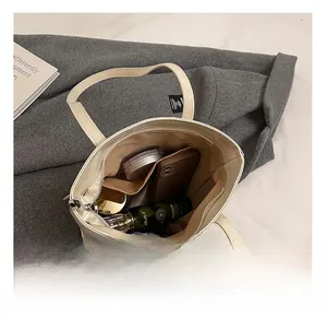 Vue intérieure montrant la grande capacité et les poches de ce sac fourre-tout blanc cassé