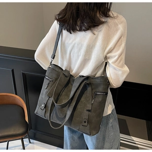 Detail view of large dark grey tote bag with side zipper and slim shoulder strap