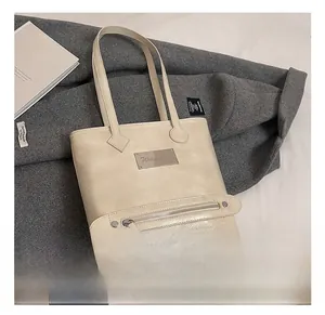 Détail du cabas en cuir beige avec plaque en métal et poche décorative zippée sur le devant