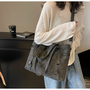 Detail view of large charcoal grey tote bag with adjustable strap and metallic side zippers