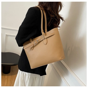 Détail du sac cabas en cuir grainé camel avec boucle argentée porté par un mannequin