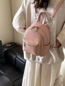 Pink mini leather backpack with woven texture and silver metal zippers on a model