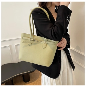 Détail du sac cabas vert clair avec texture litchi et boucle en métal sur costume noir