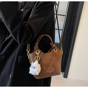 Braune glänzende Beuteltasche mit Knotengriff und Plüschkatzen-Anhänger Detail