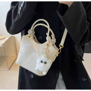 Detail der weißen Lackleder-Beuteltasche mit Plüsch-Anhänger und Knotengriff-Design