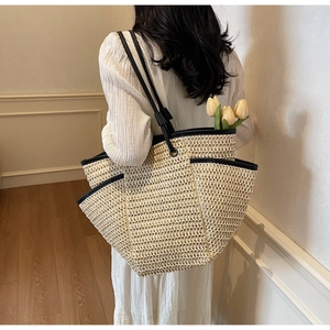 Close-up of woven straw tote bag with black PU trim and long shoulder straps