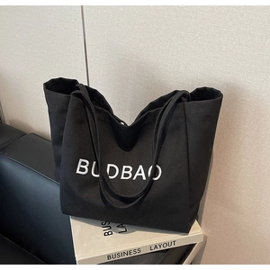 Macro view of the thick black canvas material and white BUDBAO lettering on the tote bag