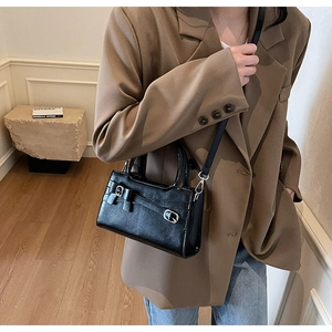Detailed view of black leather handbag with decorative silver bow buckle and strap details