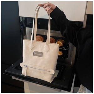 Detail of cream tote bag with wrinkled faux leather texture and metal brand plaque