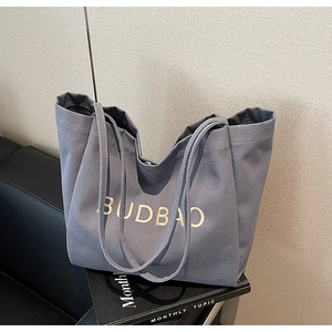 Close-up of the thick grey canvas tote bag with gold BUDBAO logo and long shoulder straps