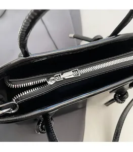 Dettaglio macro della cerniera in metallo argento e del manico annodato della borsa in pelle