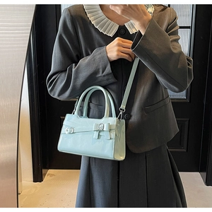 Fashionable mint green handbag with bow detail worn as a stylish crossbody bag