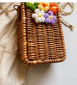 Détail du sac en paille tissé avec fleurs au crochet colorées et collier de perles