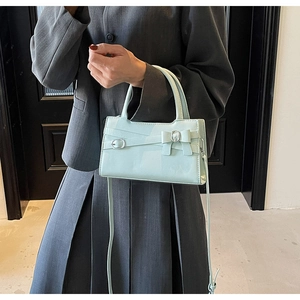 Pale mint green patent leather bag with bow detail worn with a dark grey suit