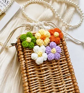 Détail d'un sac en paille tissé à la main avec fleurs au crochet et bandoulière perle