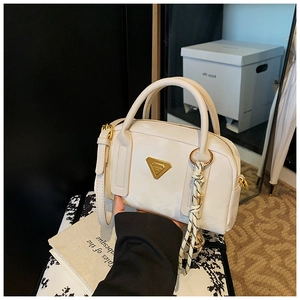 Détail du mini sac bowling blanc avec logo triangle doré et pompon tissé élégant