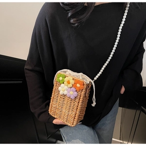 Détail du sac seau en paille fait main avec fleurs au crochet et anse en perles