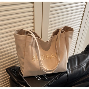 Close-up of minimalist beige canvas tote bag with BUDBAG embroidery on a leather cushion