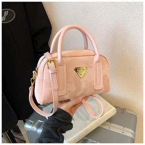 Détail du sac Boston rose avec texture nuage, logo triangle doré et doubles anses