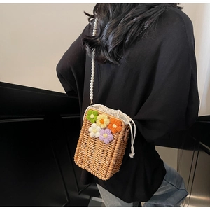 Détail du sac seau en paille avec fleurs au crochet et bandoulière en perles nacrées
