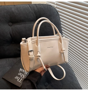 Dettaglio della borsa in pelle crema con nodi decorativi e logo del marchio in metallo