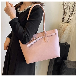 Détail du sac cabas rose en cuir grainé avec sangle décorative sur modèle élégant