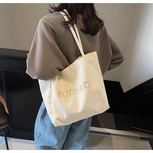 Rear view of a model wearing a minimalist beige canvas tote bag with yellow embroidery