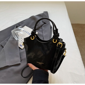 Detailansicht der schwarzen Beuteltasche mit goldenen Beschlägen und Knotengriff