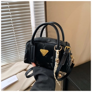 Détail du sac bowling en velours noir avec plaque dorée et pendentif tressé