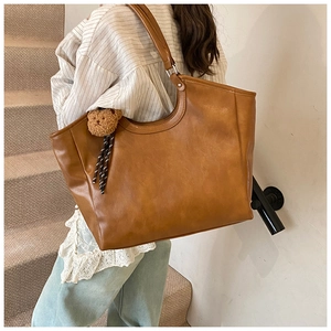 Close-up of tan PU leather tote bag with a cute brown plush bear charm detail