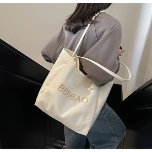 Detail of off-white canvas tote bag with BUDBAO embroidery and long shoulder straps