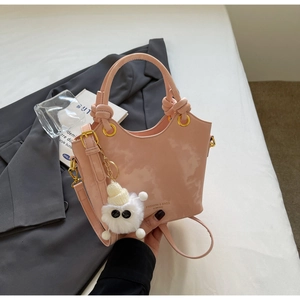 Detailansicht der rosa Lederbeuteltasche mit Wellenrand und Plüsch-Anhänger auf Sakko