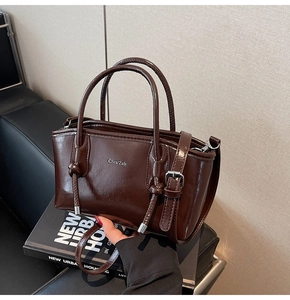 Dettaglio borsa in ecopelle marrone scuro con finitura lucida e logo argentato