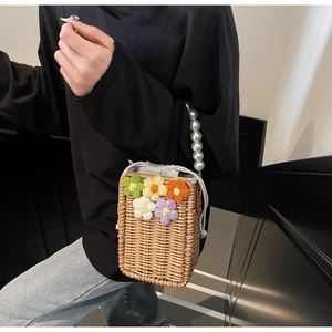 Détail du sac seau en paille avec fleurs au crochet et anse en perles blanches