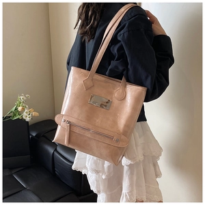 Detailed shot of large beige tote bag in glossy faux leather with metal plate detail