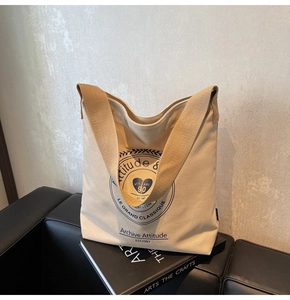 Détail du sac fourre-tout en toile avec logo bleu vintage et bandoulière marron