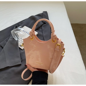 Detail der hellrosa Beuteltasche mit Marmormuster, Knotengriffen und goldener Hardware