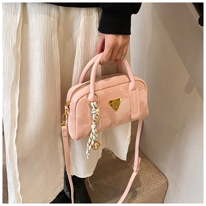 Détail du sac bowling rose avec plaque triangulaire dorée et breloque tissée chic