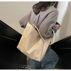 Detail of beige canvas tote bag with BUDBAO gold embroidery and slim shoulder straps