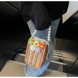 Détail du sac seau en paille avec fleurs au crochet et anse en perles élégante