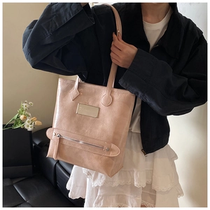 Close-up of light pink tote bag featuring textured leather and gold metal hardware detail