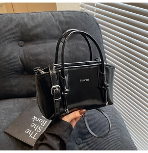 Dettaglio borsa tote nera lucida con logo argento e design del manico a nodo intrecciato