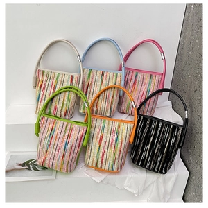 Detail of colorful striped woven bucket bags showing diverse handle colors and metal ring