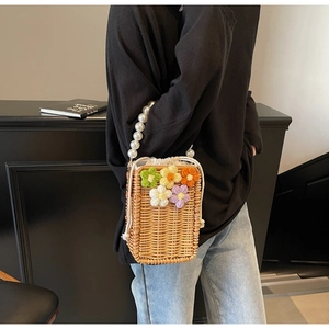 Détail du sac seau en paille avec fleurs au crochet et poignée en perles élégante