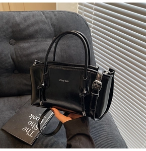 Dettaglio della borsa tote in pelle nera lucida con nodi decorativi e fibbie in metallo