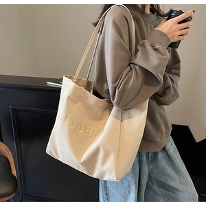 Close-up of the BUDBAG letter embroidery on a minimalist beige canvas tote bag