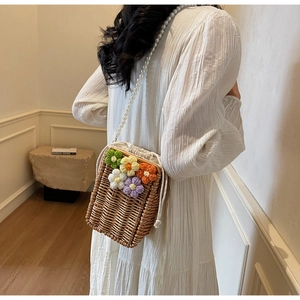 Détail du sac seau en paille avec fleurs au crochet et bandoulière en perles blanches