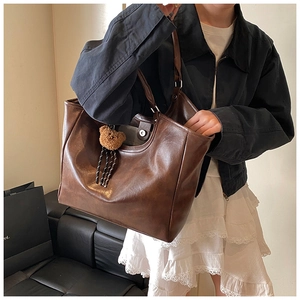 Brown faux leather tote bag with pebble texture and cute bear charm shown on model