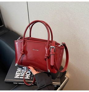 Dettaglio borsa tote in pelle lucida bordeaux con logo e lacci laterali a coulisse